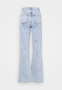 Jeans de ganga de cóshow claro, em forma de sino, com uma cintura alta, cinco bolsos e uma bainha crua nas pernas. Apresentam um desbotado subtil e costura em contraste.