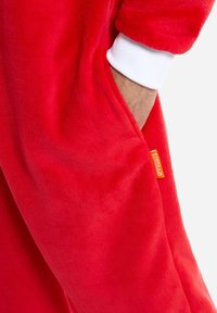 Red fleece bodysuit with white cuff, featuring a side pocket and an orange label that says "OPPOSUITS." Soft texture and plush material.