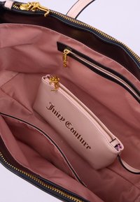 Borsa nera e rosa con un esterno liscio, hardware dorato e un interno rosa, che presenta una borsetta con zip più piccola etichettata "Juicy Couture."
