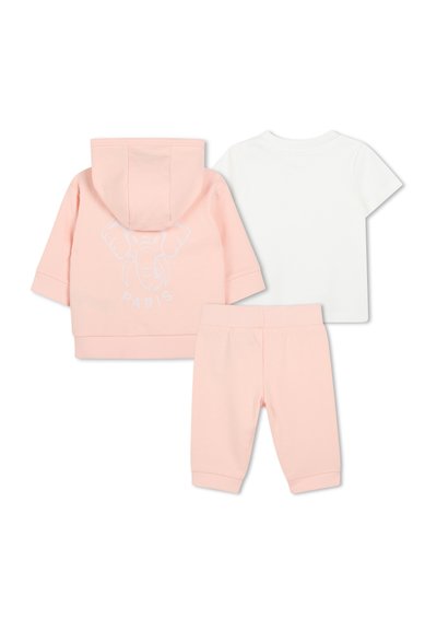 Sweat à capuche rose avec impression d'éléphant et texte "PARIS", associé à un t-shirt blanc à manches courtes et un pantalon rose. Matière en coton douce.