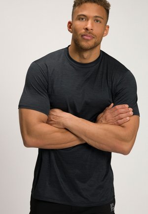 T-shirt de sport gris foncé en tissu texturé, avec des manches courtes et un col rond, porté par un mannequin avec les bras croisés.