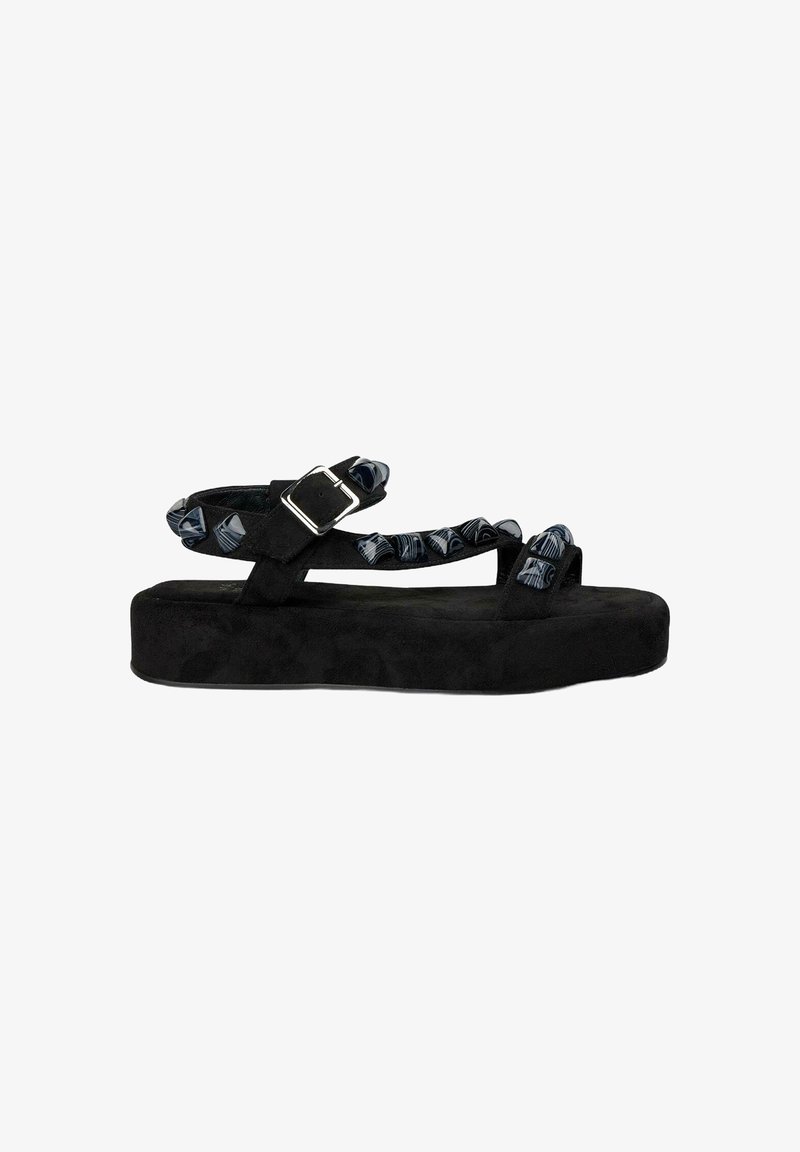 Sandalias de plataforma de ante negro con tiras de tela estampada, que cuentan con un cierre de hebilla. El diseño incluye una suela gruesa y acentos texturizados.