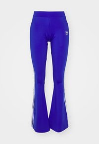 Leggings acampanados azules, hechos de material elástico, con tres franjas blancas a lo largo de cada lado y un logo blanco en la cadera izquierda.