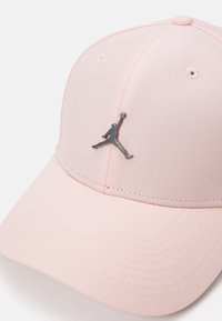 Roza kapa izrađena od teksturiranog materijala, sa zakrivljenim vizirima i crnim Jumpman logom na prednjoj strani. Šest-panelni dizajn s ventilacijskim rupama.