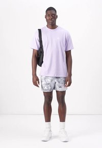 Lavender cotton T-shirt, black shoulder bag, patterned white shorts, white sneakers, and white socks. Simple, casual outfit in bright colors.