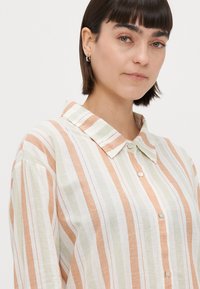 Gestreepte button-up shirt van zachte stof; heeft verticale strepen in perzik, groen en wit; klassieke kraag, knopen aan de voorkant en losse pasvorm.