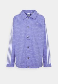 Lila jacka gjord av mjuk tyg, med ett mönster av vågiga linjer, tryckknappar och vita tre-randiga detaljer på ärmarna.