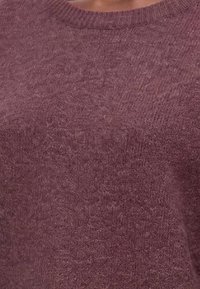 Gros plan d'un pull en maille douce violette avec un col rond côtelé porté par une personne.