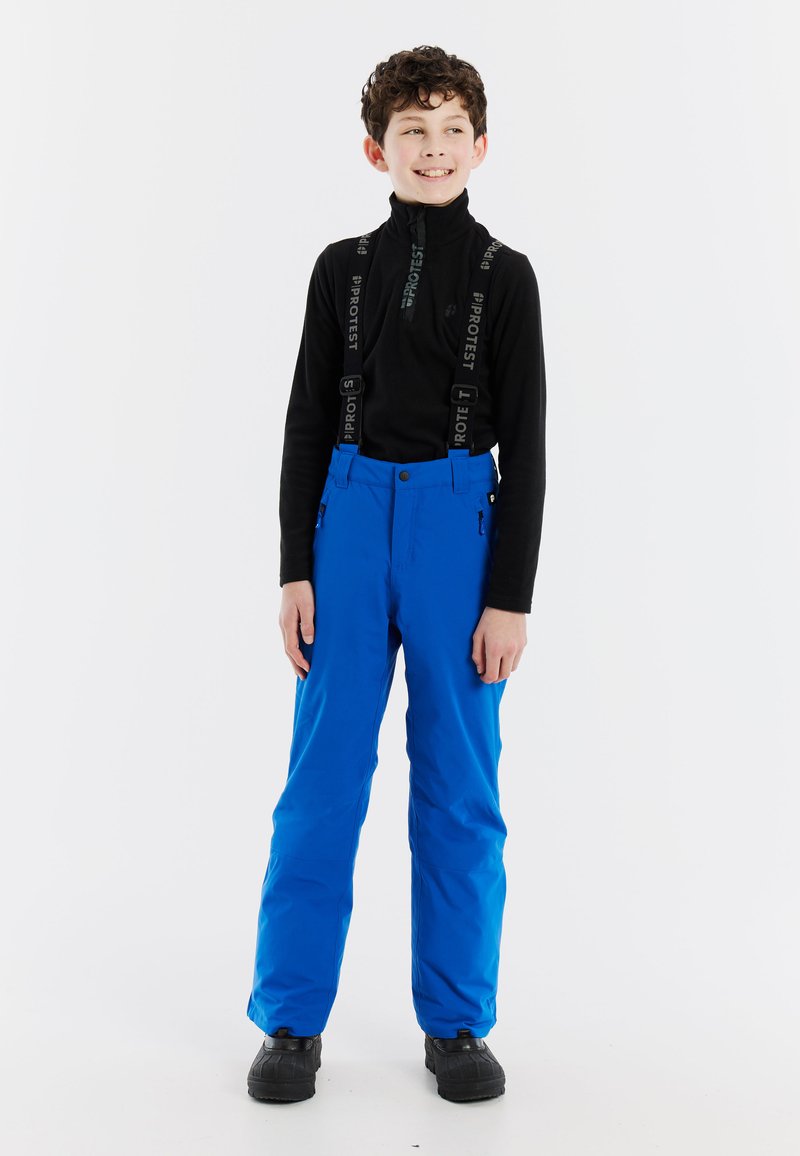 Modré zimné nohavice so nastaviteľnými čiernymi traky, vysoký pás a bočné vrecká. Nosí sa s čiernym dlhým rukávom a čiernymi topánkami.