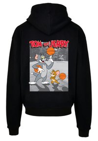 Sort hættetrøje med et frontprint af Tom og Jerry med basketballer. Designet inkluderer livlige farver og legesyge tegnefilmskarakterer.