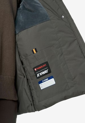 Intérieur de veste rembourrée grise avec une doublure en polaire bleue, poche poitrine affichant les logos Primaloft et K-Way, et une étiquette pour les informations personnelles.