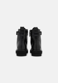 Bottes courtes en cuir noir au design élégant, avec fermetures éclair à l'arrière et sangles ajustables. Semelles en caoutchouc robustes offrant adhérence et maintien.