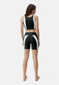 Črno-bela športna zgornja in spodnja kombinacija. Ima enotno črno barvo s kontrastnimi belimi stranskimi črtami in prilega se telesu.