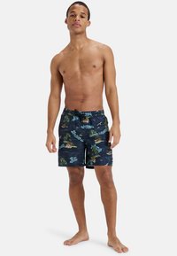 Navy swim shorts featuring a tropical pattern with palm trees and text. Made of lightweight material, designed with an elastic waistband and drawstring.