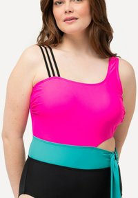 Maillot de bain une pièce avec un haut rose vif, des accents noirs et turquoise, et des bretelles noires à trois bandes. Texture lisse et découpes sur les côtés.