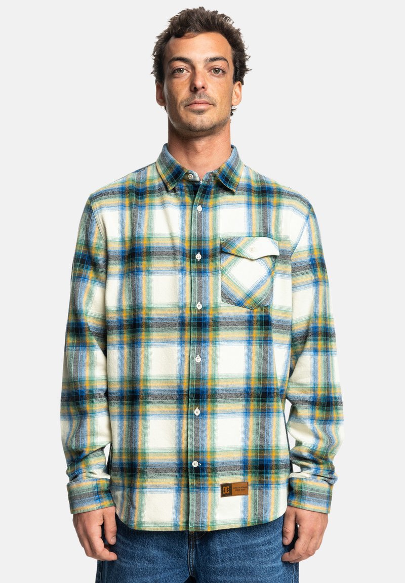 Męska koszula flanelowa z guzikami w białą, niebieską, zieloną i żółtą kratę. Posiada kieszeń na piersi oraz wplecioną metkę na dolnym brzegu.