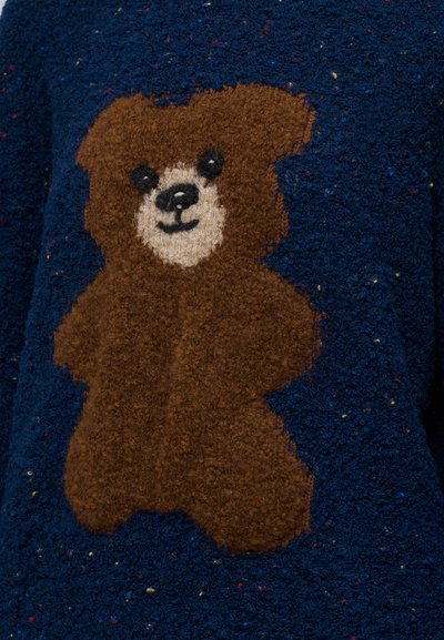 Σχέδιο καφέ αρκούδας teddy με μαύρα μάτια και μύτη σε μπλε υφασμάτινο φόντο με υφή.