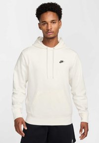 Felpa crema con tasca frontale, cappuccio regolabile con cordino e logo Nike nero sul petto. Presenta polsini e orlo a coste.