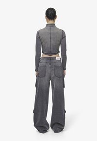 Gray denim cropped jacket with a high collar and long sleeves, paired with wide-leg gray denim pants featuring large back pockets.