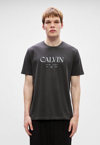 Tumehallist puuvillast T-särgist koosnev valge trükitud logo "CALVIN NEW YORK 1968" ees. Lühikesed varrukad ja ümmargune kaelus.