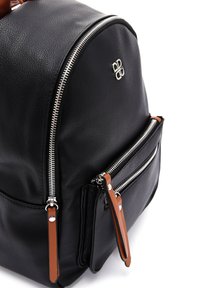 Sac à dos en cuir noir avec une forme structurée, fermetures éclair en acier inoxydable et deux poches avant dotées de tirettes en cuir marron. Détail du logo visible.