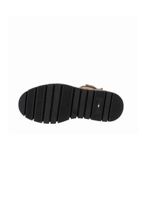 Semelle de chaussure en caoutchouc noir avec des rainures horizontales. Caractéristiques d'un accent de logo rectangulaire, d'une construction robuste et d'une forme de bout légèrement arrondie.