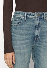 Ljust tvättade denimjeans med femficksdesign, knappstängning och sydda detaljer. Tyget har en något urblekt textur.