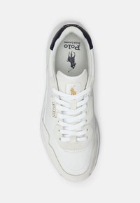 Vita läder- och mockasneakers med en texturerad yta, med en gyllene logotyp och vita snörningar. Accentuerad med en mörk marinblå hälkappa.