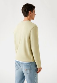 Lichtgroene sweatshirt met een ronde hals, recht model en geribbelde manchetten. Gekocht in combinatie met lichtblauwe spijkerbroek met details op de achterzakken.