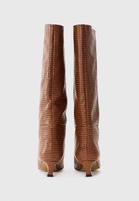 Bottes en cuir marron texturé, montant jusqu'au genou, au design élégant, avec un bout pointu et un talon effilé. Des lignes verticales subtiles ornent la surface.