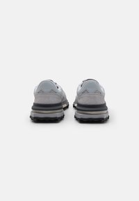 Gray sneakers featuring a mixed material design with suede and mesh. Textured rubber sole and padded collar for support.
