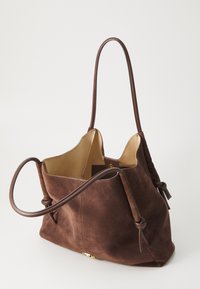 Sac fourre-tout en daim marron avec un intérieur tan, doté de longues bandoulières en cuir marron et d'une ouverture supérieure sécurisée. Design simple sans quincaillerie visible.