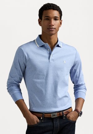 Lichtblauwe lange mouwen polo met een witte kraagaccent en een klein logo op de borst, gecombineerd met donkere denim jeans en een leren bruine riem.