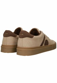 Zapatillas bajas de ante beige con un acento marrón y suelas de goma. Presentan puntera redondeada, delantero con cordones y detalle del logo en el talón.