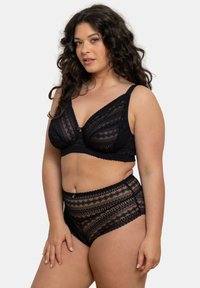 Ensemble en dentelle noire comprenant un soutien-gorge et une culotte taille haute, ornés de motifs géométriques, de bords festonnés et d'un accent doré au centre. Tissu doux et texturé.