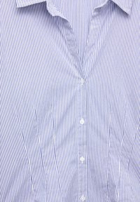 Vaaleansininen ja valkoinen pystysuunnassa raidallinen nappipaita, jossa kaulus, lähikuva, jossa keskitytään nappeihin ja kankaan tekstuuriin.