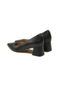 Dei tacchi alti neri in pelle con punta affusolata e tacco a blocco spesso. Presentano una texture liscia e dettagli sottili sul retro.