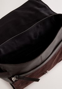 Geantă din piele maro și velur, cu interior din material textil negru, închidere cu fermoar și accesorii argintii. Dispune de un singur compartiment pentru depozitare.