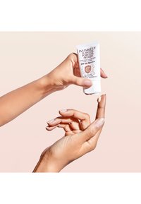 Il primer invisibile UV Flawless Poreless in un tubo bianco. Il primer viene dosato su un dito, mostrando un colore beige chiaro e una consistenza liscia.