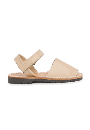 Sandalia de cuero beige con diseño de punta abierta, correa ajustable y suela de goma negra texturizada. Presenta costuras blancas a lo largo de los bordes.