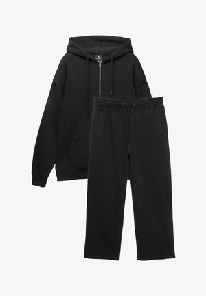 Black hoodie with a zip, large front pocket, and ribbed cuffs paired with matching black jogger pants featuring an elastic waistband and side pockets.