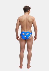 Blå simbyxor med ett livligt mönster av gula och orange grafiska designer. Slätt material med en figurnära form.