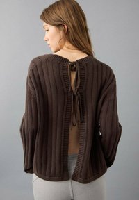 Brauner gerippter Pullover mit Rückenknotenverschluss, einem Bootsausschnitt und lockerem Schnitt. Der strukturierte Stoff verleiht Tiefe und Interesse.