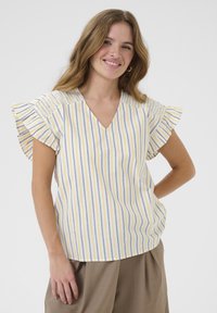 Blusa a rayas en blanco, amarillo y púrpura, con escote en V, mangas con volantes y detalles fruncidos en los hombros. Tejido suave.