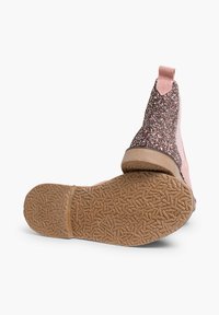 Bottines roses avec un dessus pailleté et une semelle en caoutchouc texturée. Le talon est doté d'une languette pour un enfilage facile.