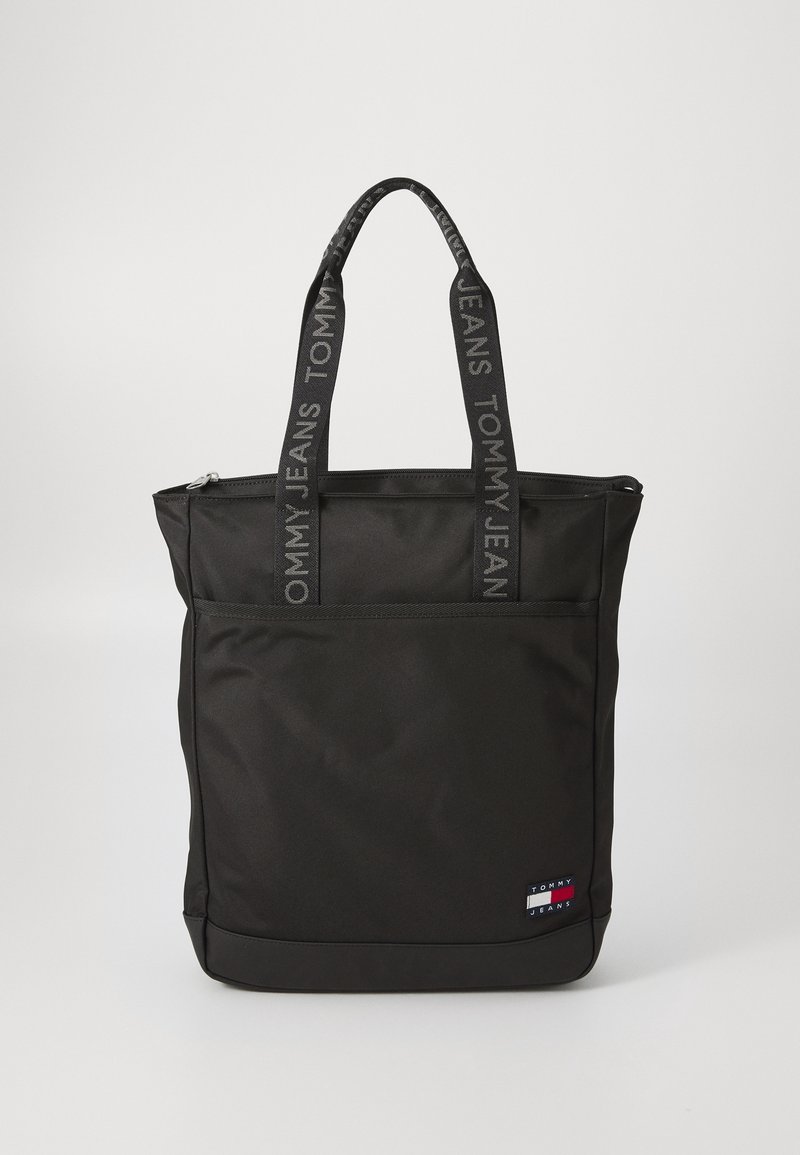 Sac fourre-tout Tommy Jeans noir avec poignées de marque et poche avant, arborant un petit logo Tommy Jeans en bas à droite.