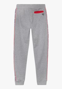 Grijze sweatpants met elastische tailleband, rode accentzak en zijstrepen met branding in marineblauw en wit. Glad stoftextuur.