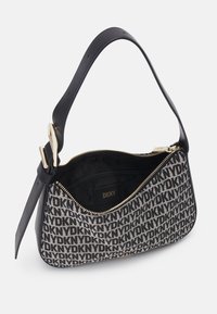 Czarna i kremowa torebka z powtarzającym się wzorem logo, zamknięciem na zamek błyskawiczny oraz gładkim skórzanym paskiem na ramię z akcentem złotego metalu.