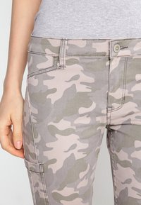 Khaki cargo kalhoty s maskáčovým vzorem v odstínech zelené a béžové, s předním zapínáním na knoflík a bočními kapsami.