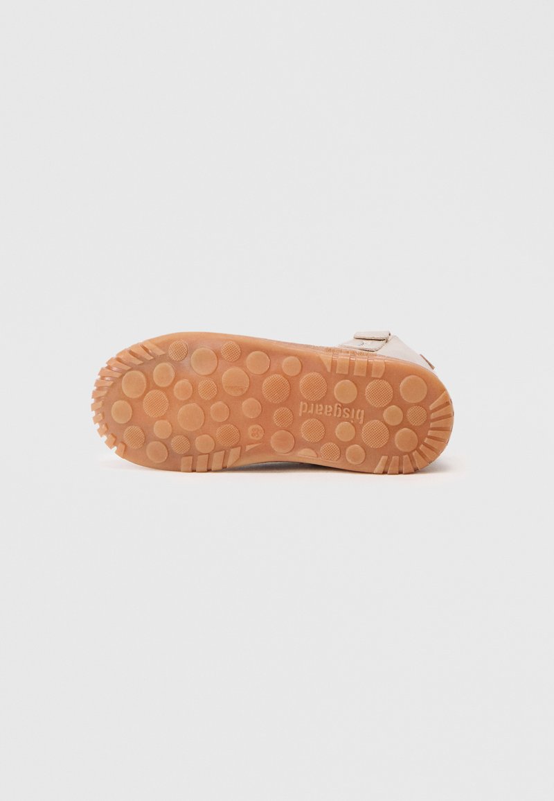 Beige Gummisohle mit kreisförmigen und strukturierten Profilmustern, mit flacher Bauweise und mit Branding versehen.